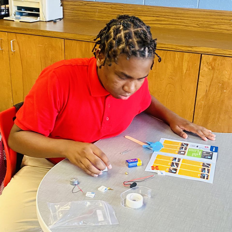 A boy looking at instructions and materials to make something.